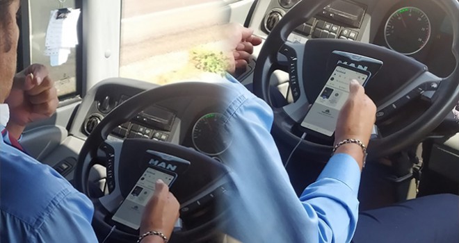 Şehirlerarası otobüs şoförünün bir elinde telefon, bir elinde çekirdek